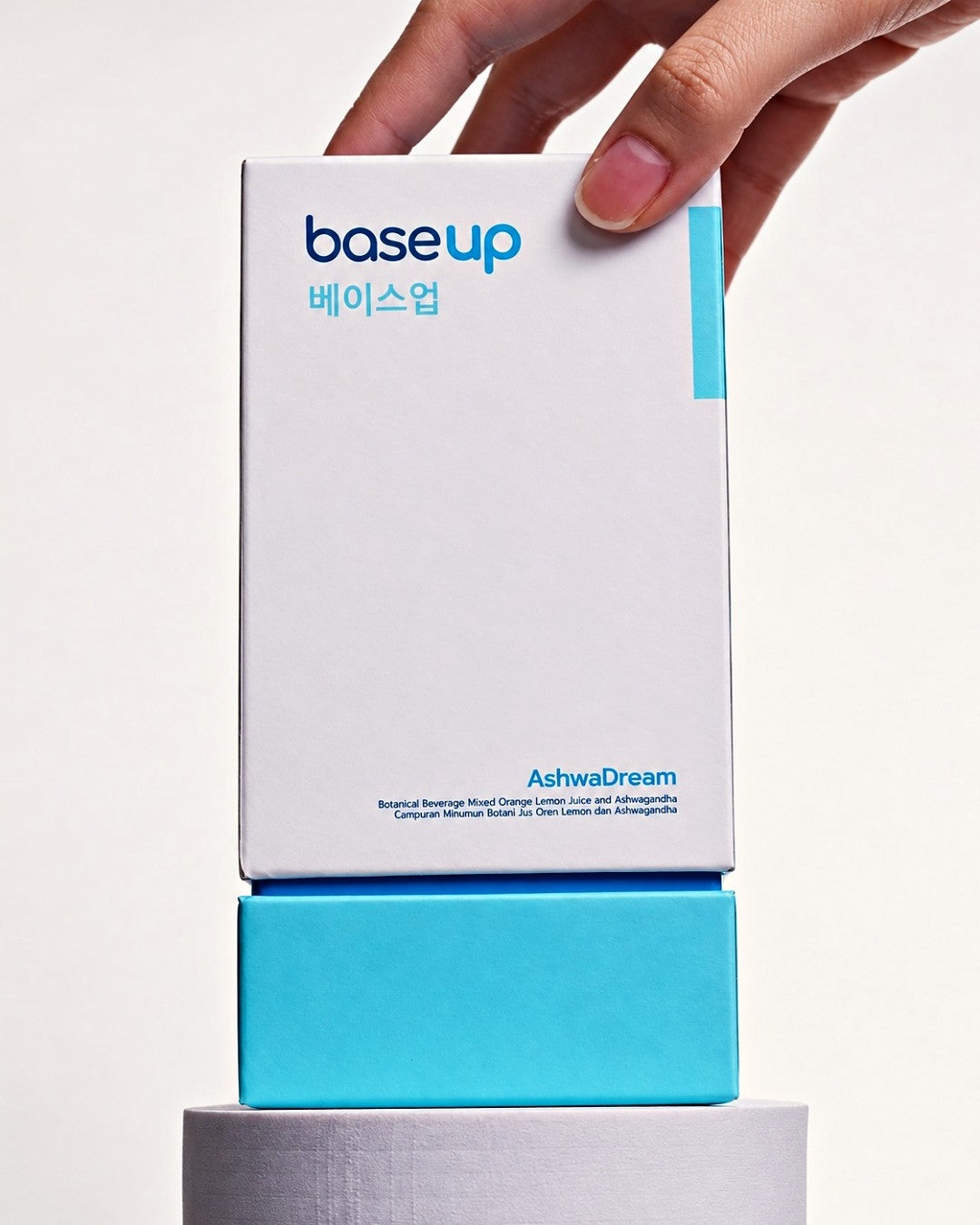A hand setting an AshwaDream box on a stand