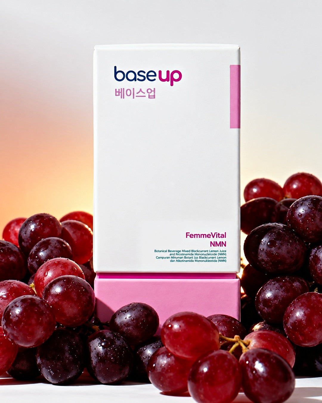 A FemmeVital NMN box among red grapes, lit from behind