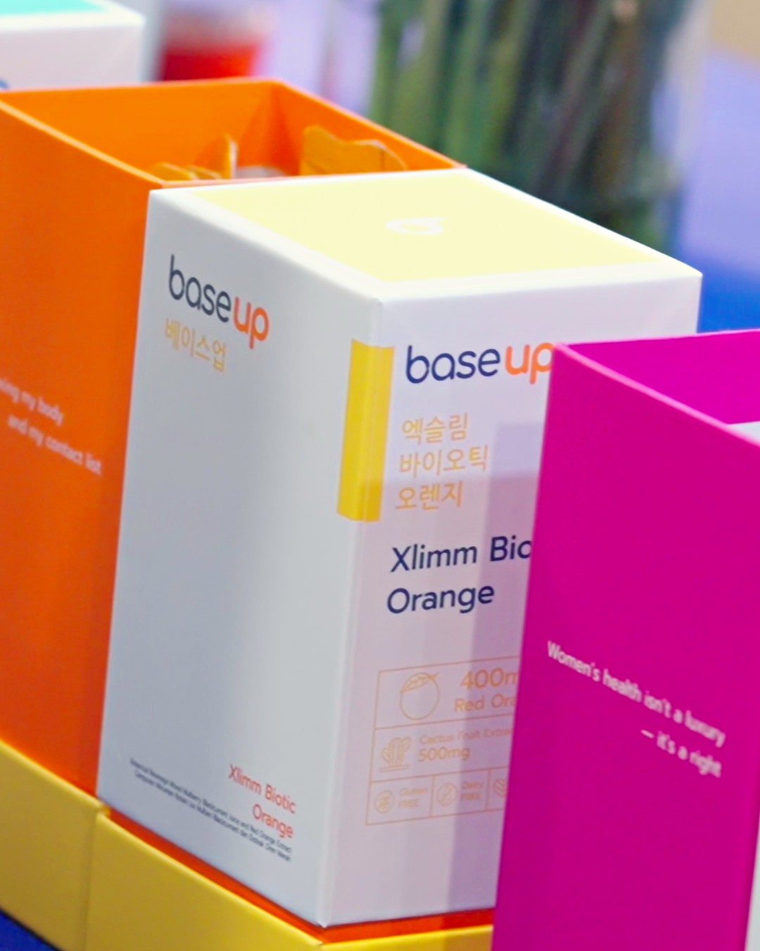 Xlimm Biotic Orange and FemmeVital NMN boxes on display at the Base Up launch event, with the dose printed on the box