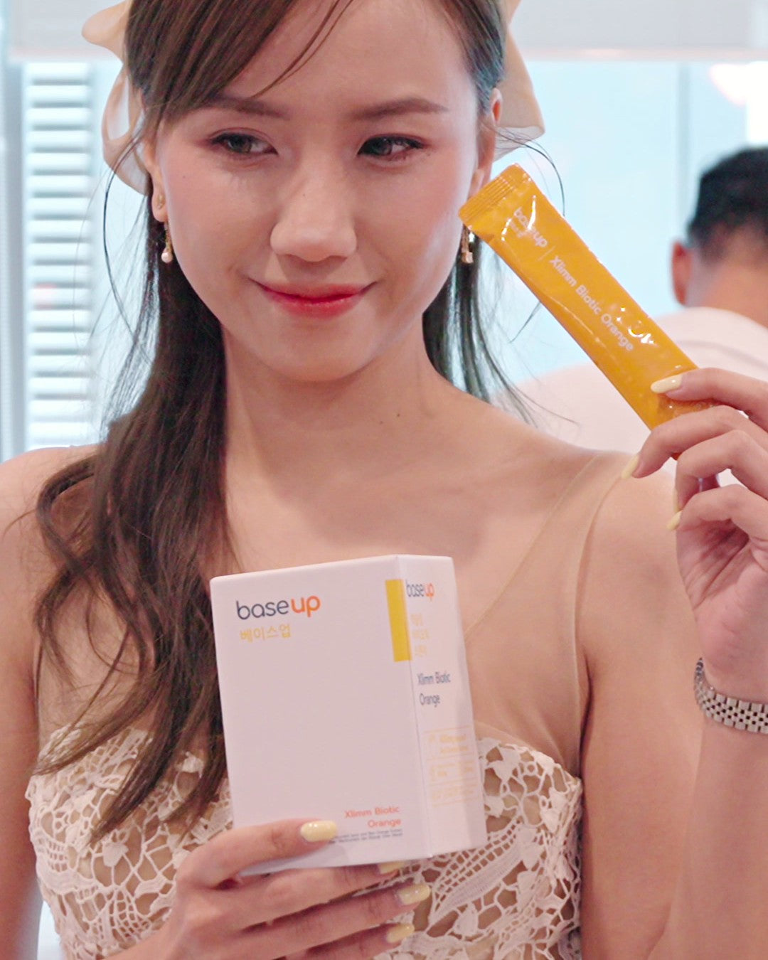 A woman at the Base Up launch event holding an Xlimm Biotic Orange box and sachet